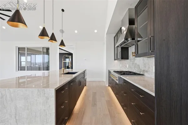 a open kitchen with kitchen island a stove a sink a center island and wooden floor