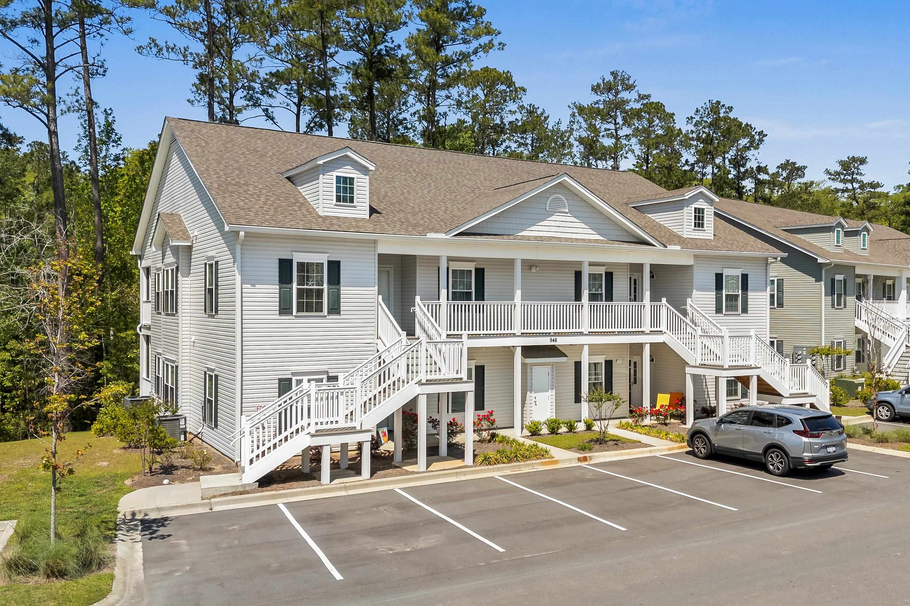 View of property featuring stairs and uncovered parking
