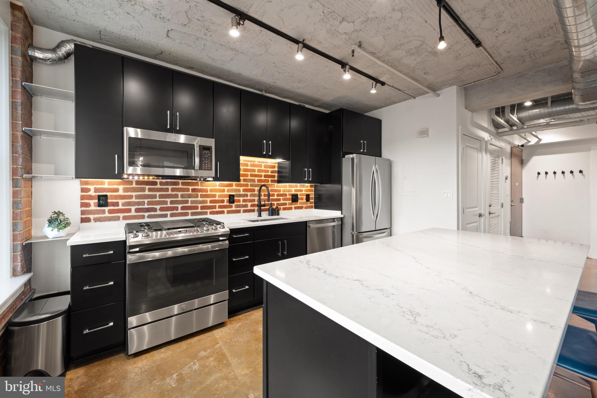 916 G St. Northwest, Unit 903 Washington, DC 20001 - Photo 15 of 65 a kitchen with stainless steel appliances kitchen island granite countertop a stove and a refrigerator
