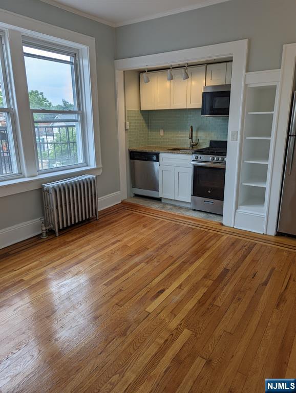 85 Anderson Street, Unit C6 Hackensack, NJ 07601 - Photo 4 of 8 an empty room with wooden floor and windows