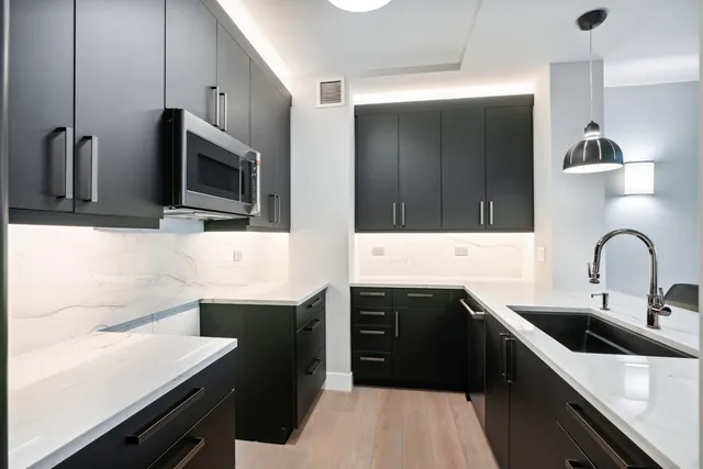 a kitchen with a sink and a stove top oven with wooden floor
