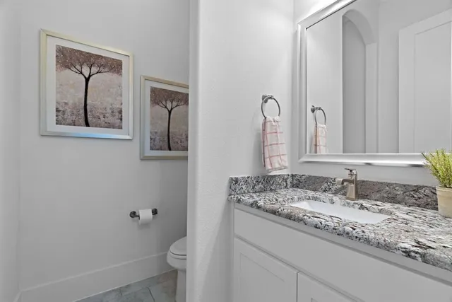 a bathroom with a granite countertop toilet sink and mirror