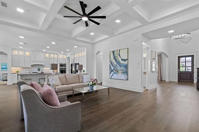 a living room with furniture kitchen view and a wooden floor