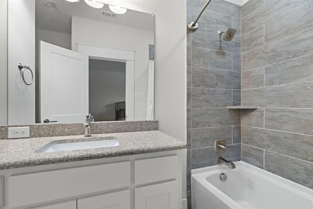a bathroom with a granite countertop sink a mirror and a bathtub