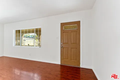 an empty room with wooden floor closet and windows