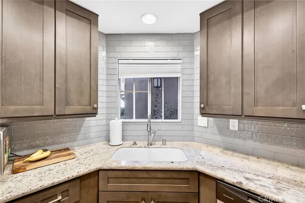 a kitchen with granite countertop stainless steel appliances a sink window and cabinets