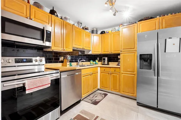 a kitchen with stainless steel appliances granite countertop a refrigerator a stove and a sink
