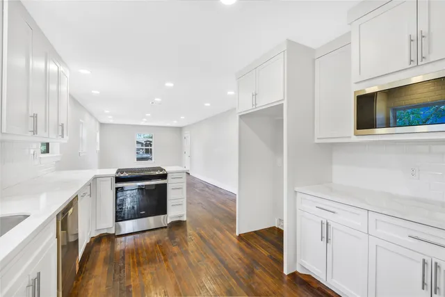 a kitchen with stainless steel appliances granite countertop a sink a stove a microwave and wooden floors