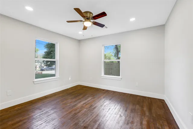an empty room with wooden floor and ceiling fan