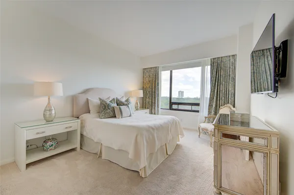 a spacious bedroom with a bed a couch and a flat tv screen on the dresser