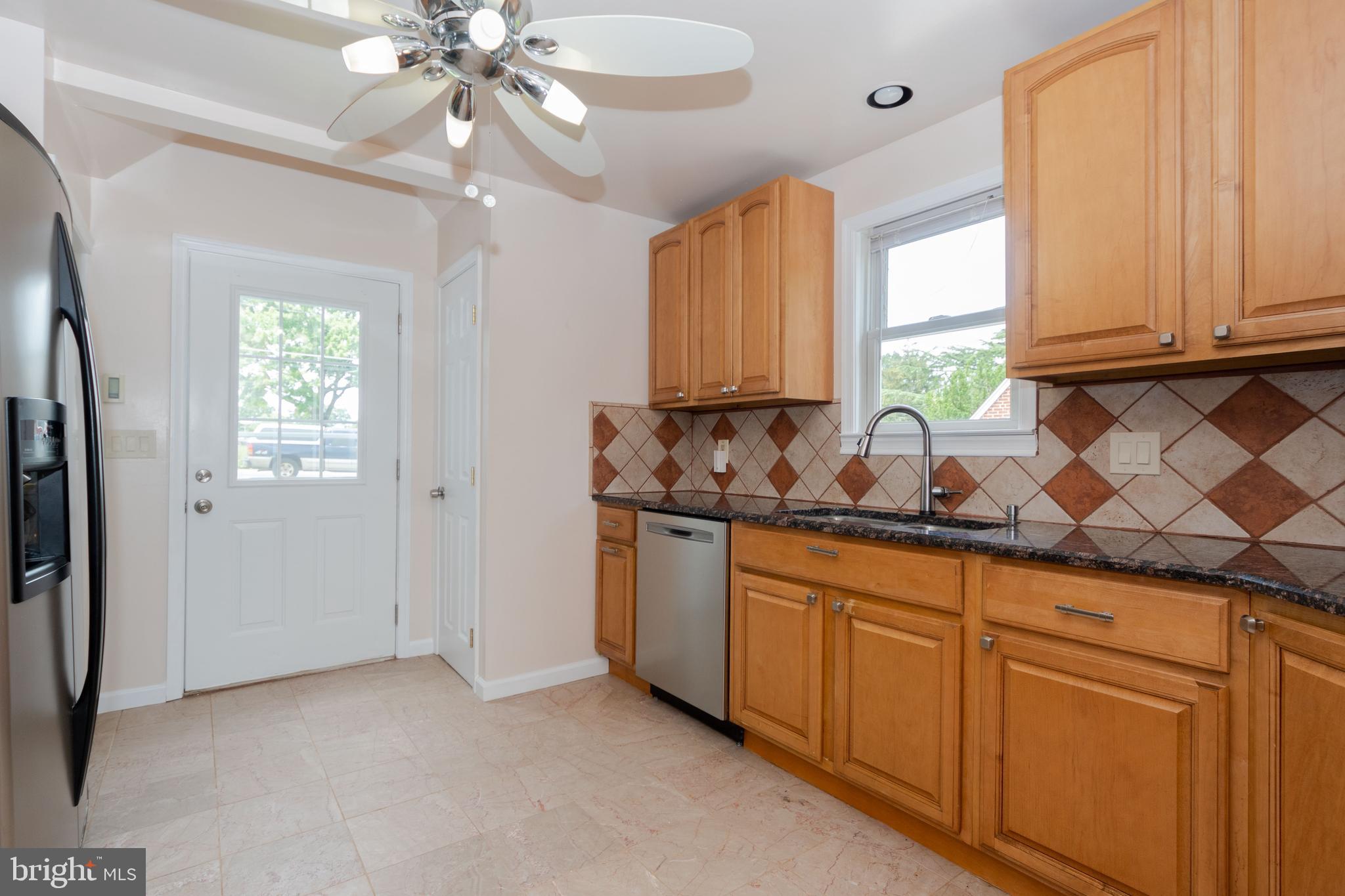 6414 Kenwood Avenue Rosedale, MD 21237 - Photo 16 of 60 a kitchen with granite countertop white cabinets white appliances a sink and a window