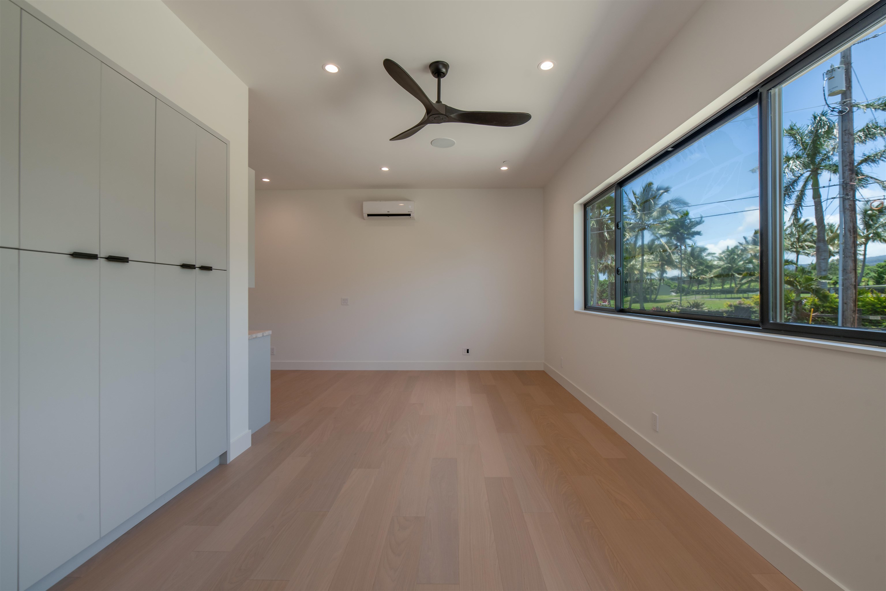 111 Mehana Road, Unit A Haiku, HI 96708 - Photo 39 of 50 an empty room with large windows and a ceiling fan