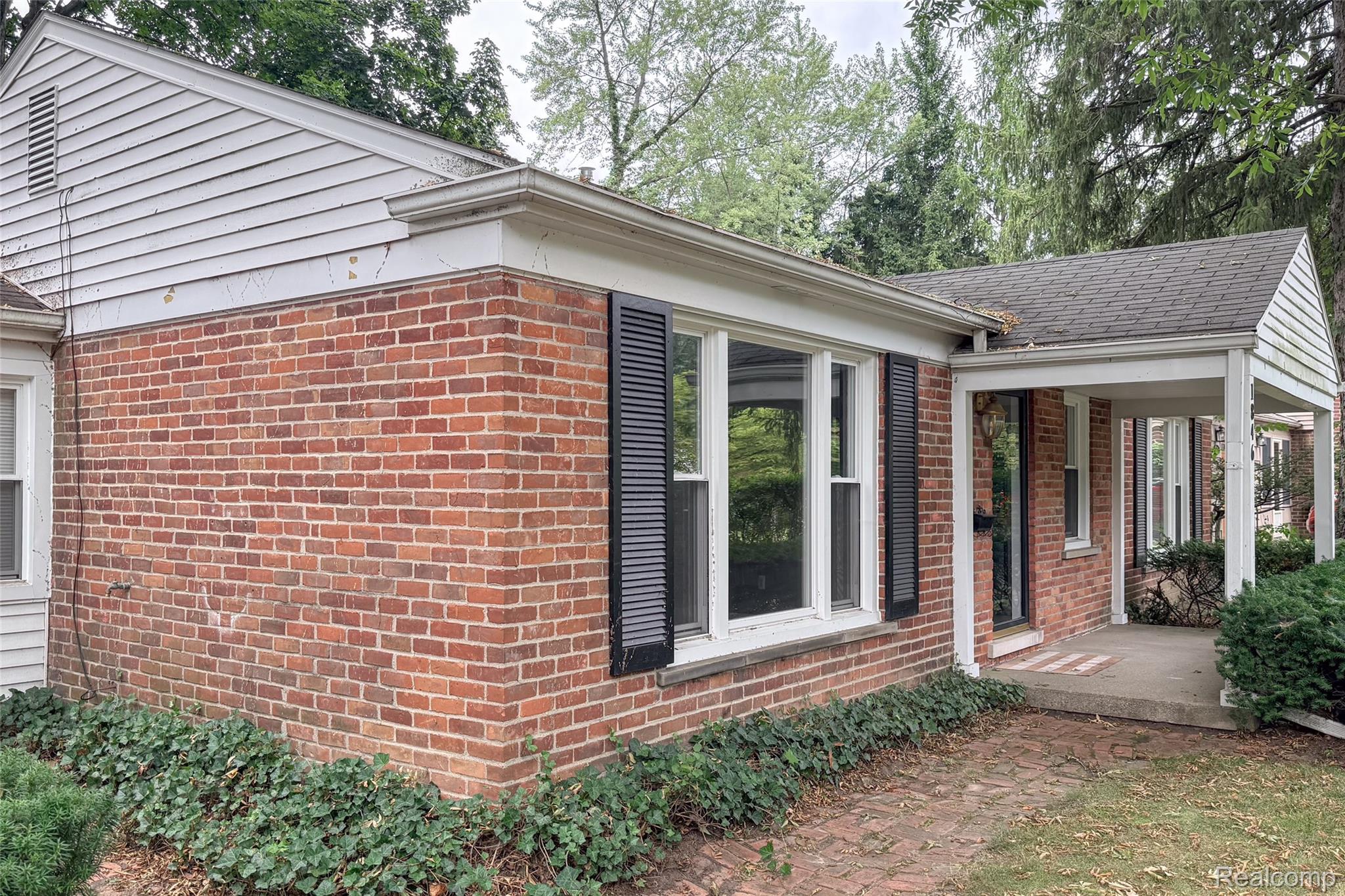 1846 Pembroke Road Birmingham, MI 48009 - Photo 4 of 37 Brick exterior with white siding accents, covered front entry, and mature landscaping