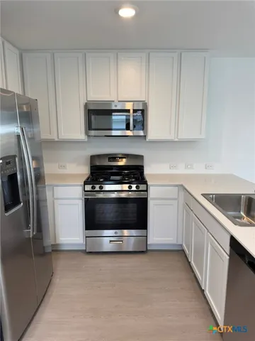 a kitchen with cabinets stainless steel appliances and a counter space