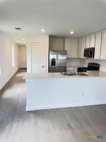 a large kitchen with stainless steel appliances a large counter top a stove and a refrigerator