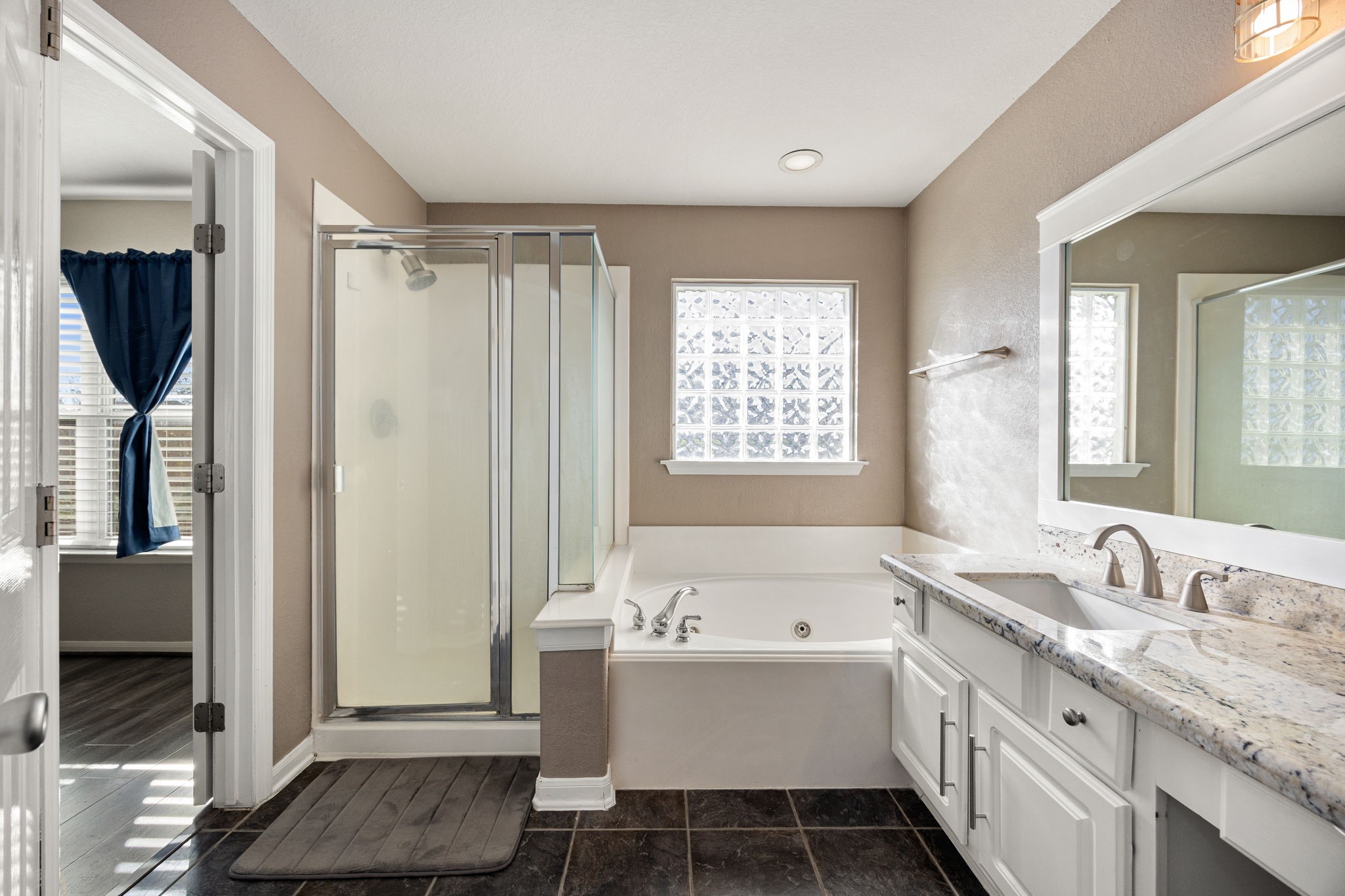 25515 Twister Trail Spring, TX 77373 - Photo 20 of 33 This bathroom features a modern glass shower, a spacious soaking tub, and granite countertops. Natural light fills the room through a large frosted window, enhancing the neutral color palette and providing a relaxing atmosphere.