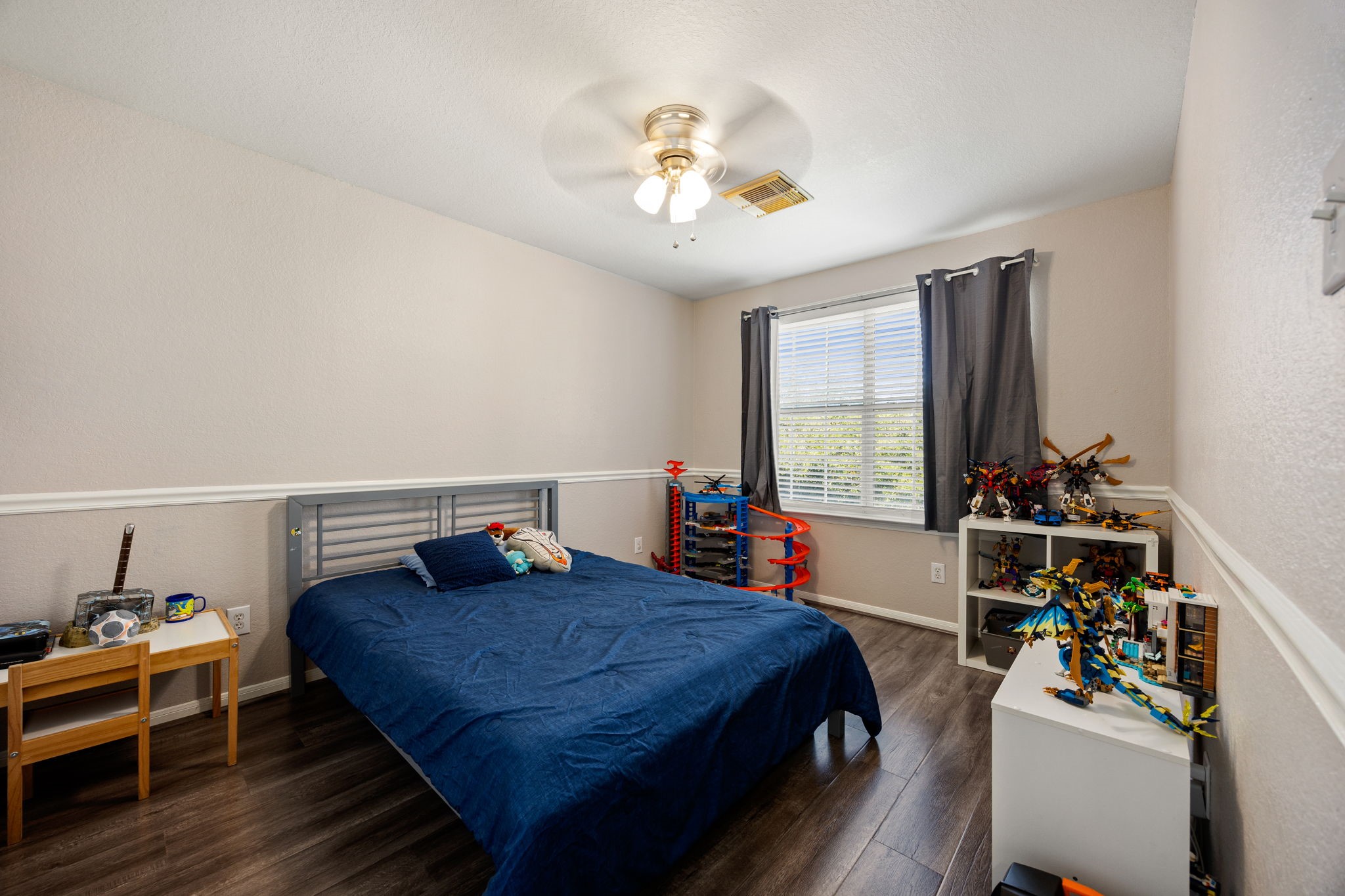 25515 Twister Trail Spring, TX 77373 - Photo 23 of 33 This cozy bedroom features a modern ceiling fan, wood flooring, and a large window for natural light. It's perfect for a child's room with space for a bed and shelves for toys or decor. The neutral wall color offers a versatile backdrop for any style.