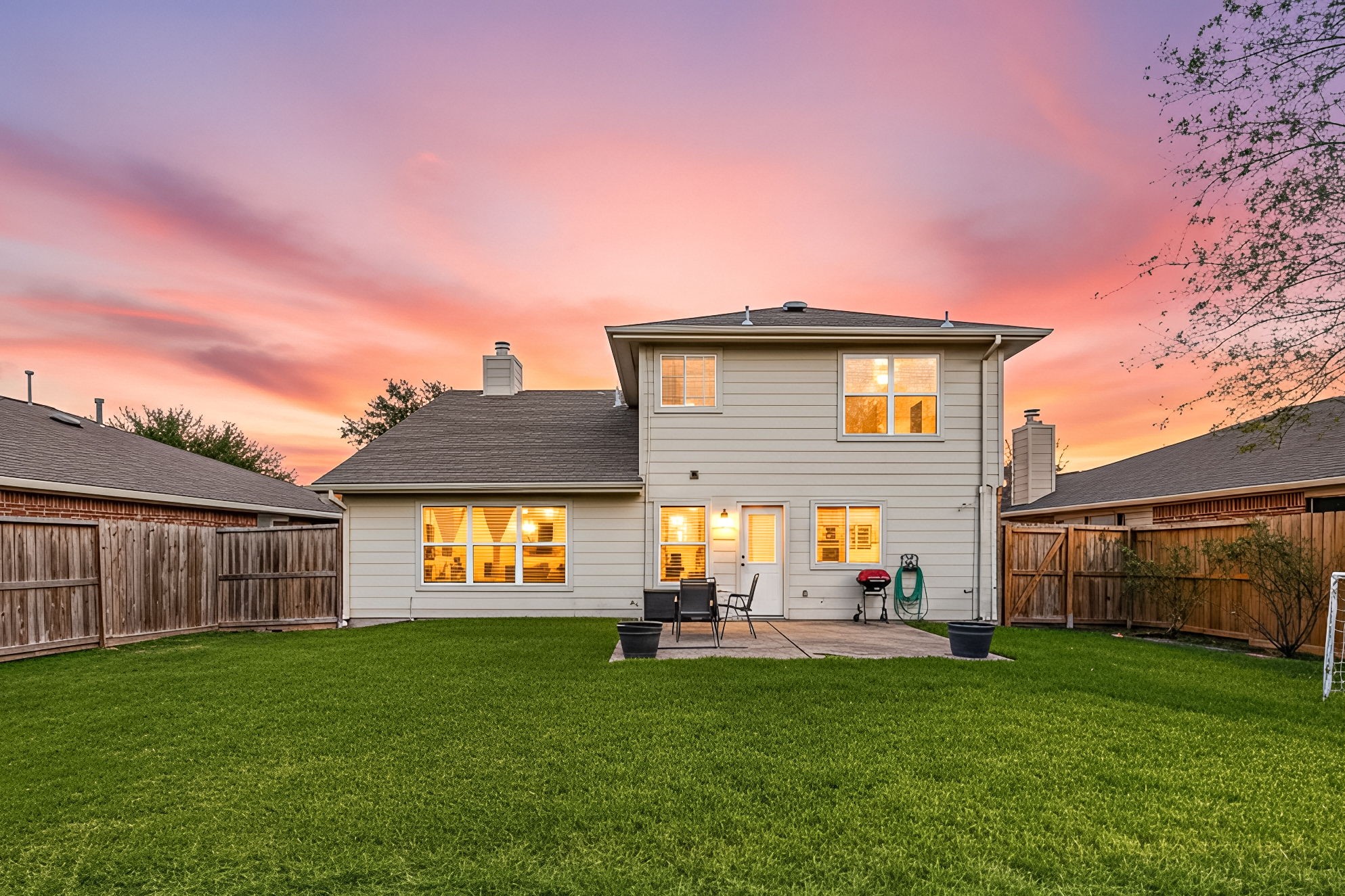 25515 Twister Trail Spring, TX 77373 - Photo 26 of 33 This photo showcases a two-story home with a spacious, well-maintained backyard. It features a patio area perfect for outdoor furniture and entertaining, all set against a beautiful sunset sky.