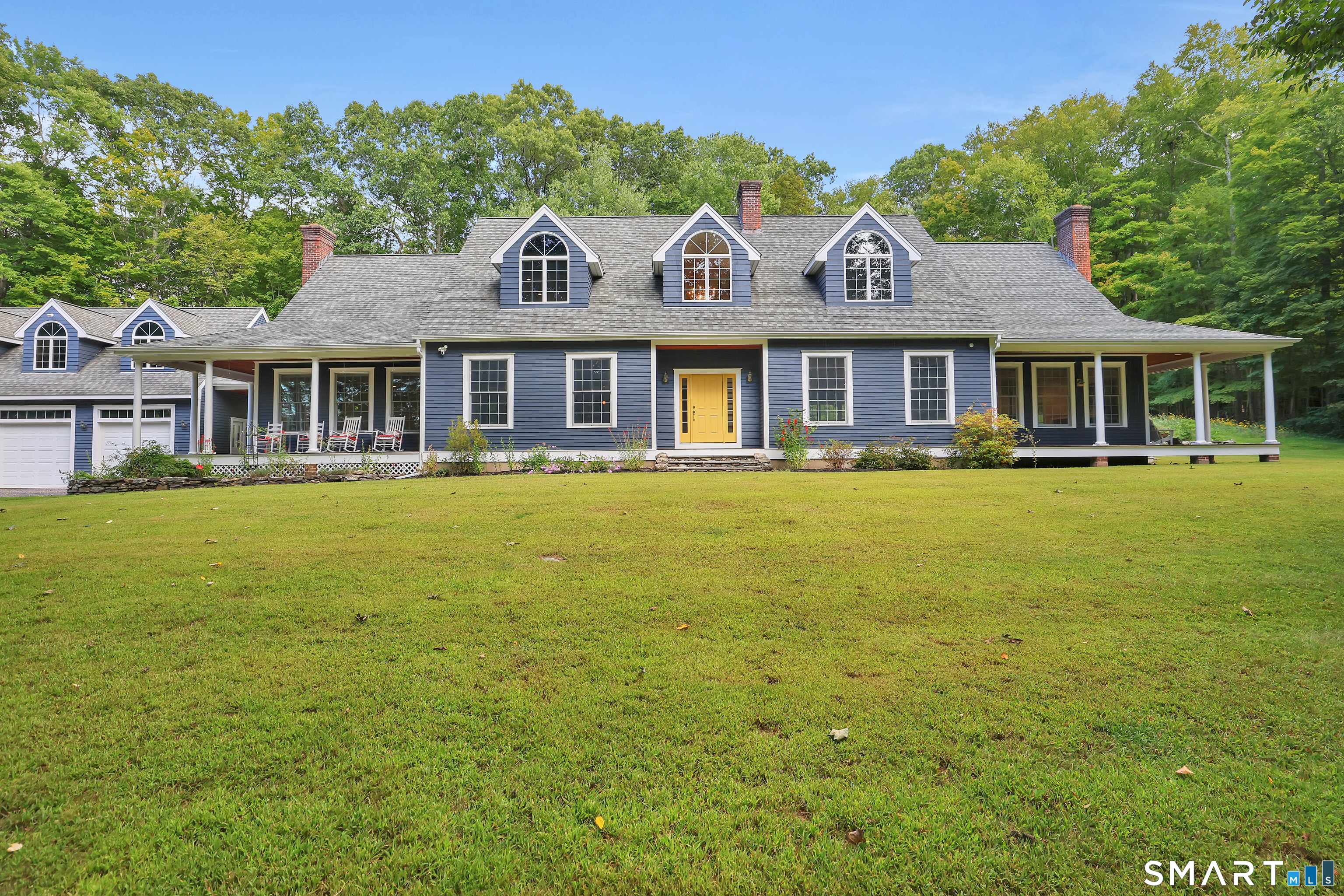 a front view of a house with garden and trees