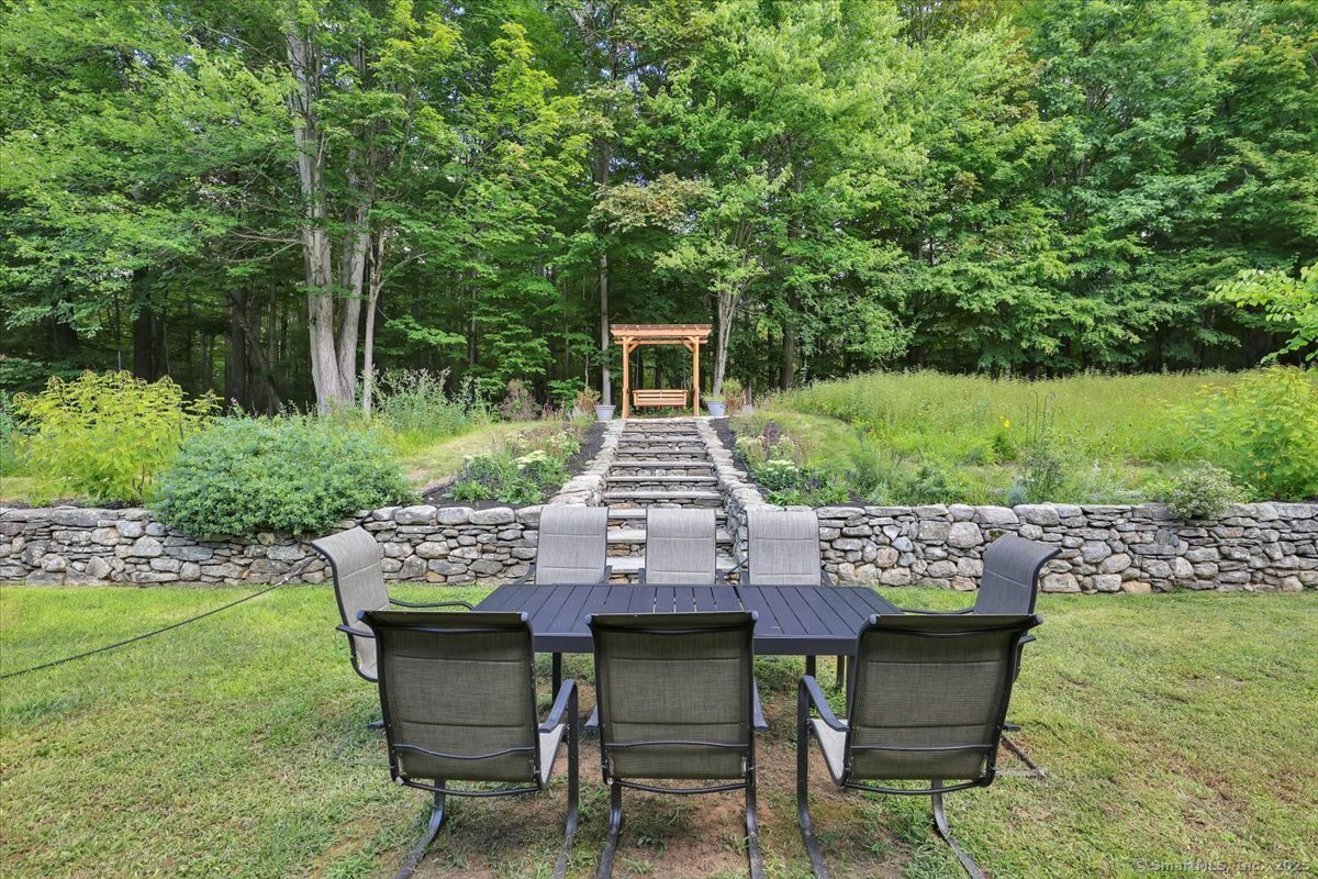 152 Cheney Lane Coventry, CT 06238 - Photo 35 of 49 The back yard is complete with stone walls and stairway that lead to the arbor w. Beautiful perennial flower gardens flank the arbor adding pops of color to the yard