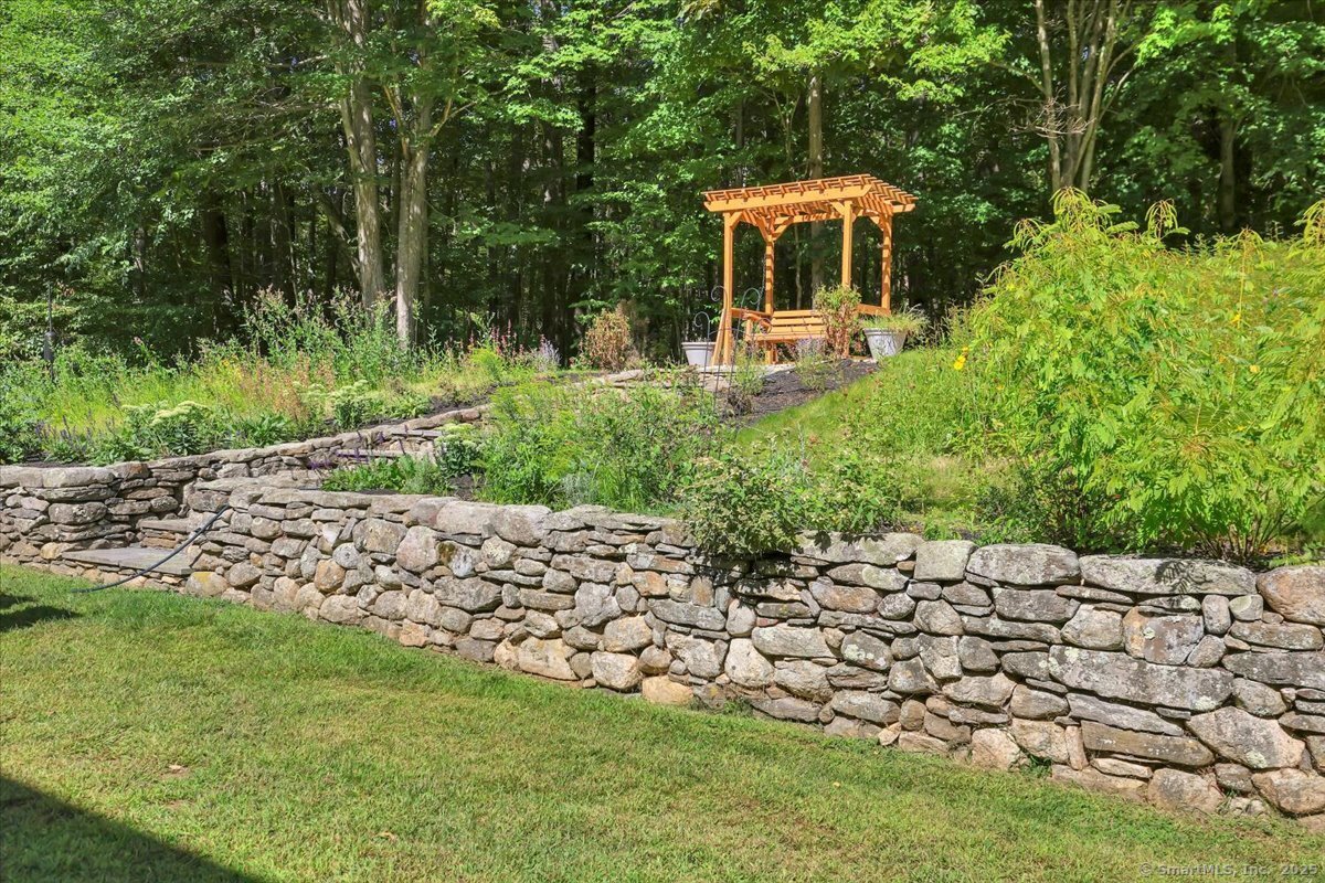 152 Cheney Lane Coventry, CT 06238 - Photo 37 of 49 Stone walls flank the stone stairway leading to the arbor and flower beds.
