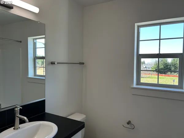 a bathroom with a toilet sink a window and mirror