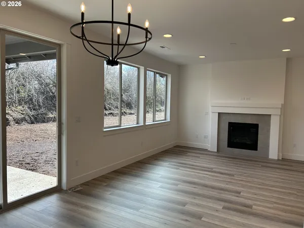 a view of empty room with wooden floor and chandelier