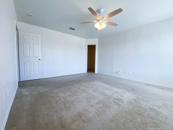 a view of an empty room with a chandelier fan