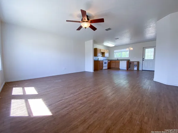 a view of empty room with wooden floor and ceiling fan