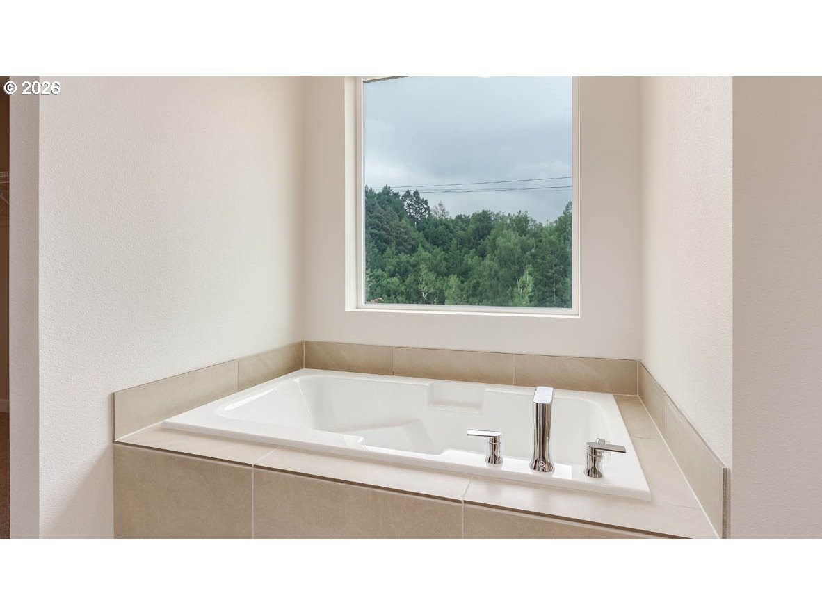 9194 Southeast Azalea Street Happy Valley, OR 97086 - Photo 29 of 32 a white bath tub sitting in a bathroom next to a window