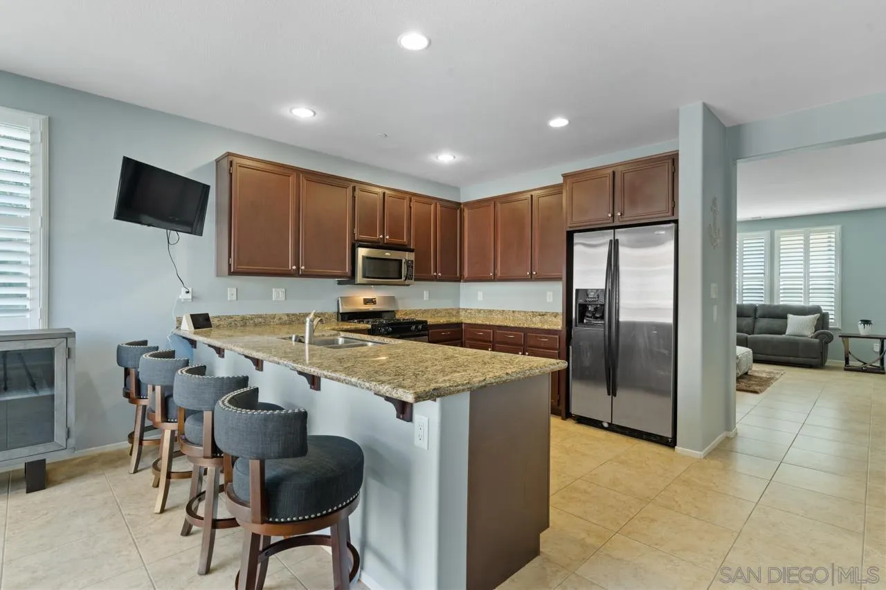 9811 Old Tree Lane Santee, CA 92071 - Photo 14 of 45 a kitchen with stainless steel appliances granite countertop a refrigerator a stove a sink a dining table and chairs
