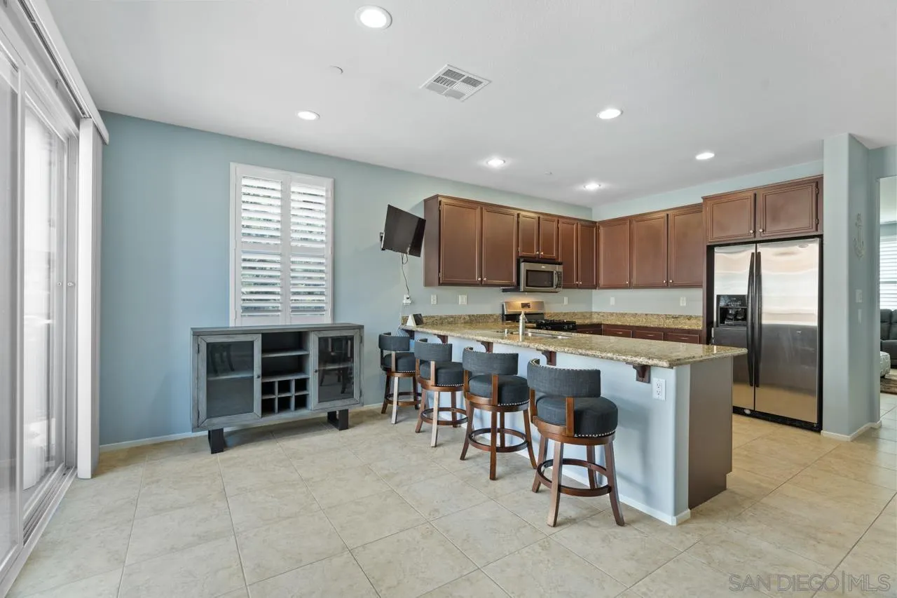 9811 Old Tree Lane Santee, CA 92071 - Photo 15 of 45 a kitchen with kitchen island granite countertop a stove a sink a oven a dining table and chairs