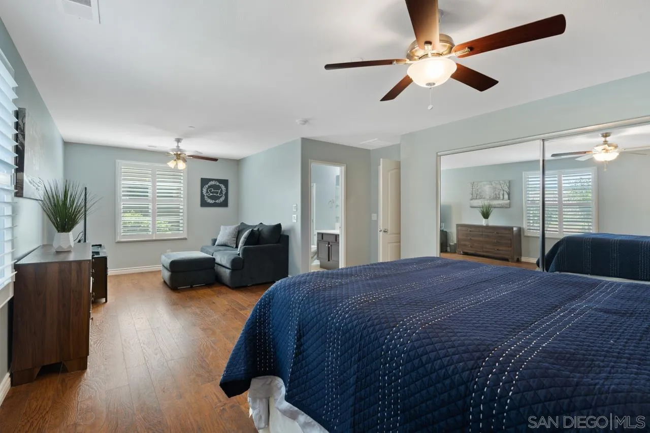 9811 Old Tree Lane Santee, CA 92071 - Photo 28 of 45 a bedroom with a bed a couch and potted plant with wooden floor