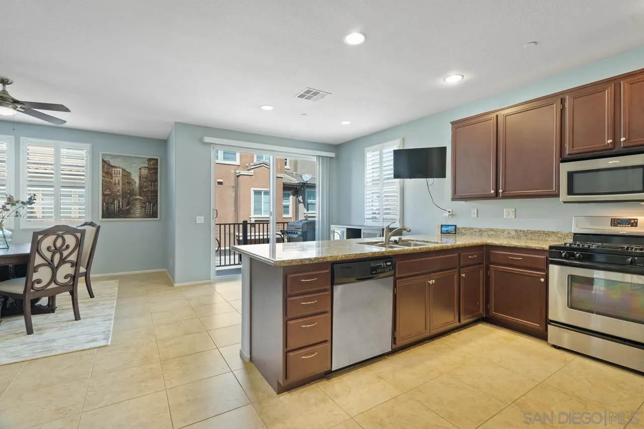 9811 Old Tree Lane Santee, CA 92071 - Photo 6 of 45 a kitchen with stainless steel appliances granite countertop a stove top oven a sink dishwasher a dining table and chairs with wooden cabinets