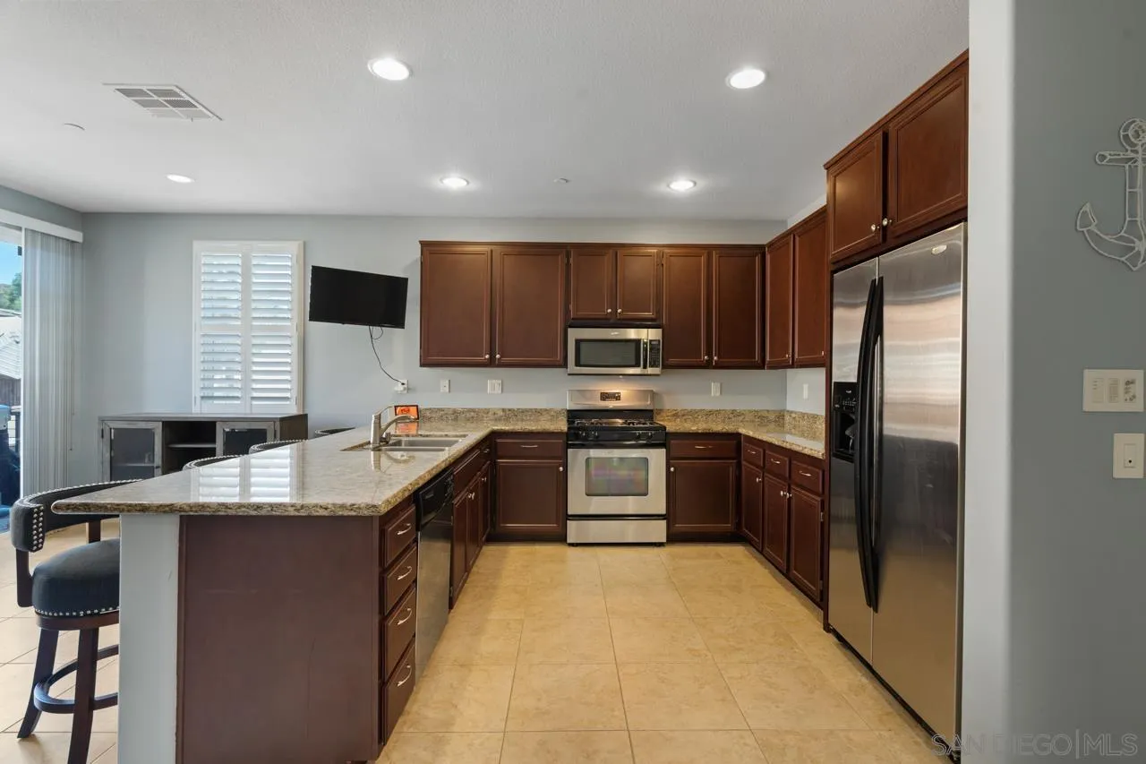 9811 Old Tree Lane Santee, CA 92071 - Photo 10 of 45 a large kitchen with stainless steel appliances granite countertop a sink refrigerator stove and microwave