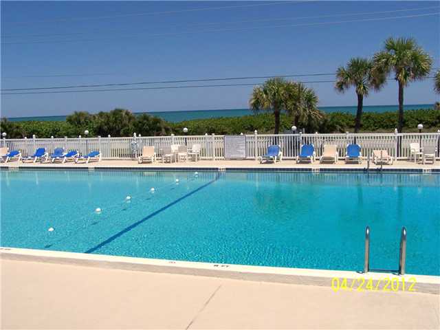 5301 Ebbtide Way Fort Pierce, FL 34949 - Photo 9 of 14 a view of a swimming pool with a lawn chairs under palm trees