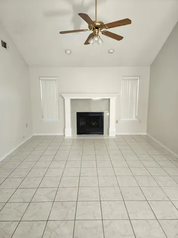 a view of an empty room with a fireplace and a chandelier fan