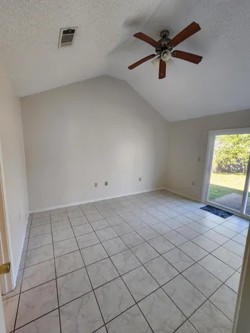 an empty room with windows and fan