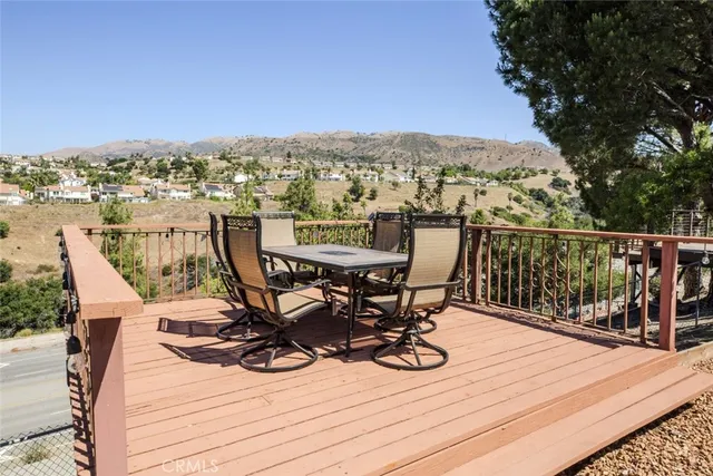 a view of a roof deck with wooden fence and a couple of chairs