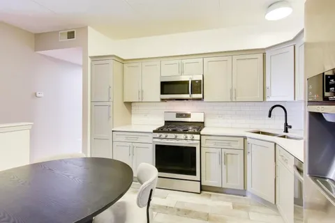 a kitchen with stainless steel appliances granite countertop a stove a sink a microwave a refrigerator and white cabinets