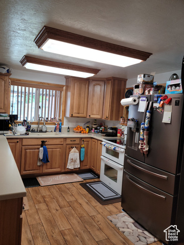 97 East Main Street Stockton, UT 84071 - Photo 36 of 58 Kitchen featuring stainless steel appliances, light countertops, light wood-style floors, and a textured ceiling