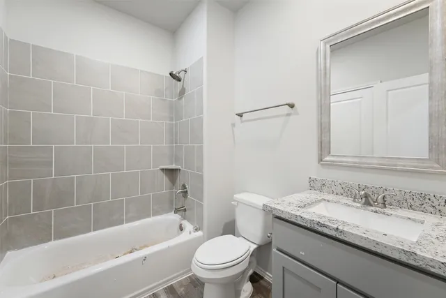 a bathroom with a granite countertop sink a toilet and bathtub