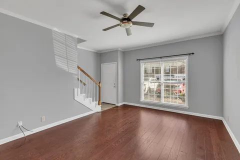 an empty room with ceiling fan fireplace and wooden floor