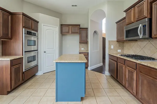 a kitchen with stainless steel appliances granite countertop a refrigerator and a stove top oven