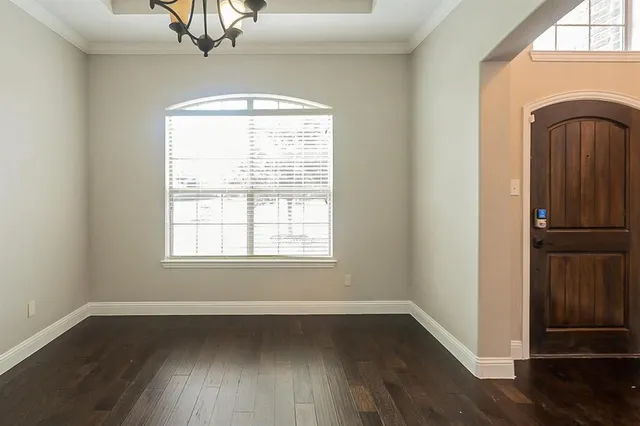an empty room with wooden floor closet and windows