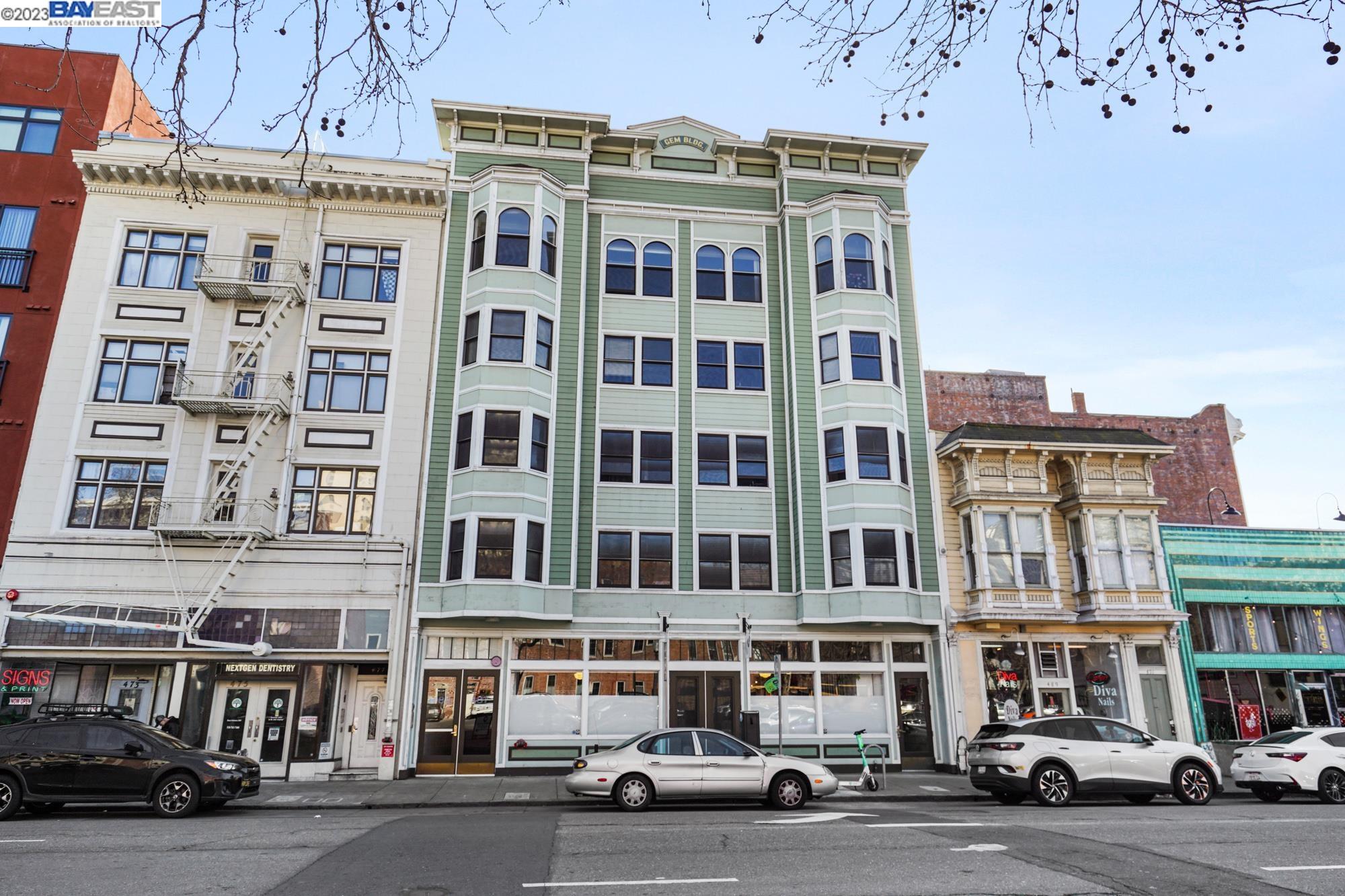 a front view of a building with lot of cars and trees