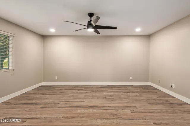 a view of an empty room with wooden floor and a window