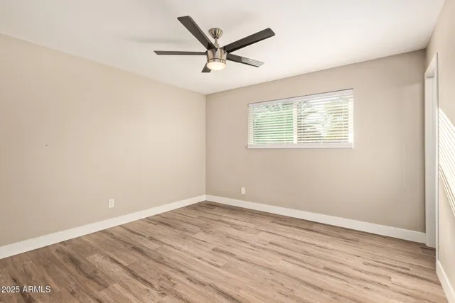 an empty room with wooden floor ceiling fan and windows