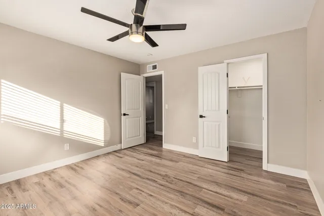 a view of empty room with wooden floor and fan