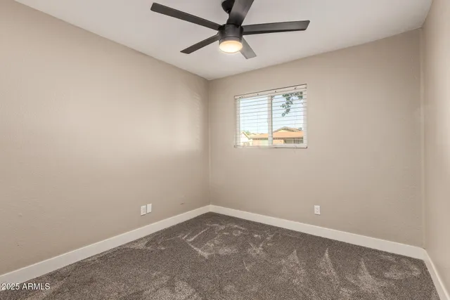 an empty room with a window and a fan